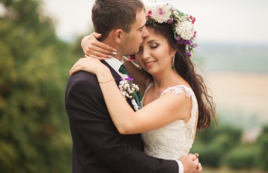 Güzel, romantik bir düğün. Yeni evliler. Eski kalenin yakınlarında sarılıyorlar.