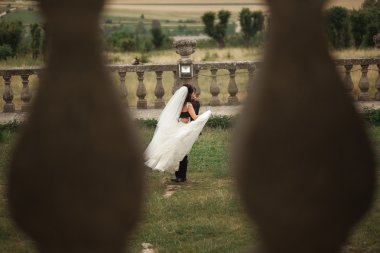 Güzel, romantik bir düğün. Yeni evliler. Eski kalenin yakınlarında sarılıyorlar.