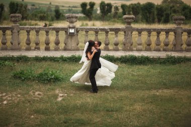 Güzel, romantik bir düğün. Yeni evliler. Eski kalenin yakınlarında sarılıyorlar.