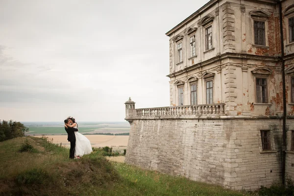 Joyeux couple de mariage embrassant et embrassant sur fond vieux château — Photo