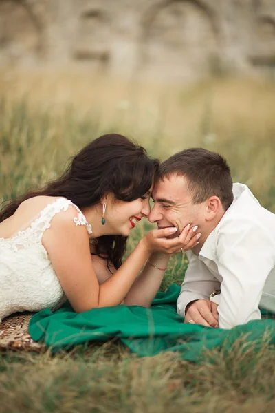 Casal de casamento feliz deitado na grama verde na hora de verão — Fotografia de Stock