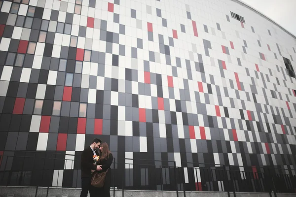 Elegante hermosa pareja posando cerca de edificio de vidrio moderno — Foto de Stock