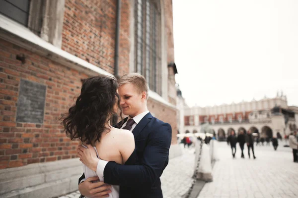 Gorgeous wedding couple, bride, groom posing near old gate building — Stock Photo, Image