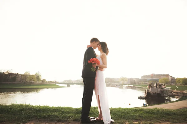 夕暮れ時、川の近くポーズ エレガントな美しい結婚式のカップル — ストック写真