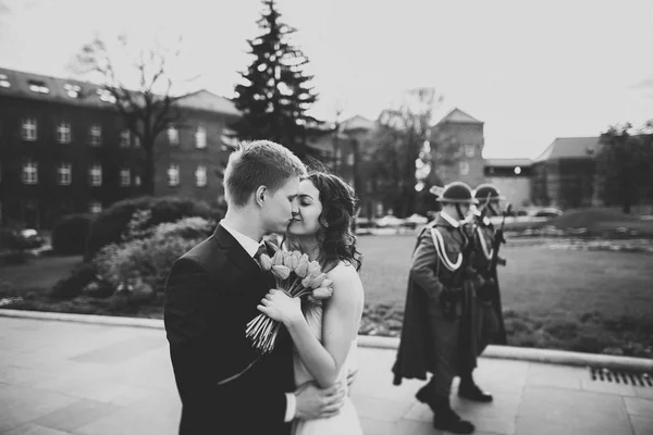 Joyeux couple de mariage étreignant et souriant sur le fond des soldats — Photo