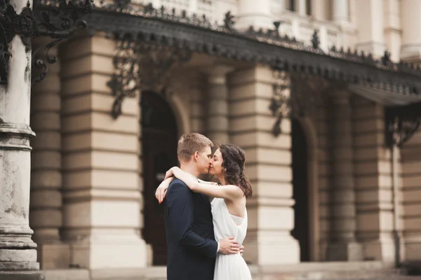Gyönyörű esküvői pár, menyasszony, vőlegény, csókolózás, és átölelte a háttérben a színház — Stock Fotó
