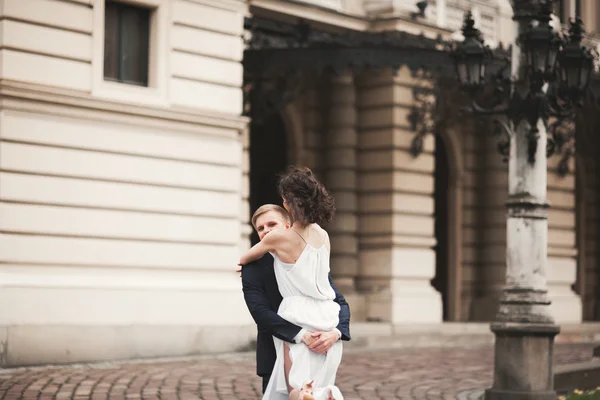 Beautiful wedding couple, bride, groom kissing and hugging against the background of theater — Stock Photo, Image