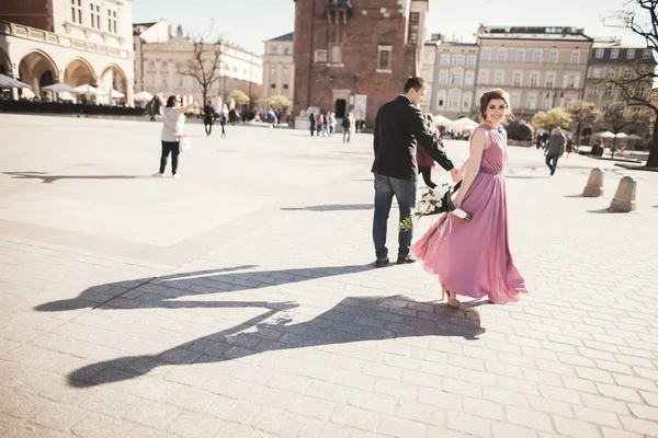 Mariage. beau couple, mariée avec robe rose marchant dans la vieille ville de Cracovie, leurs ombres — Photo