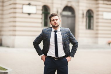 Yakışıklı, şık, genç bir iş adamı. Açık havada portre pozu veriyor.