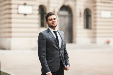 Yakışıklı, şık, genç bir iş adamı. Açık havada portre pozu veriyor.