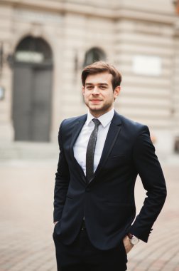 Yakışıklı, şık, genç bir iş adamı. Açık havada portre pozu veriyor.