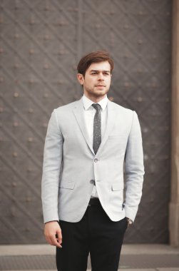 Yakışıklı, şık, genç bir iş adamı. Açık havada portre pozu veriyor.