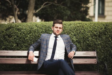 Yakışıklı, şık, genç bir iş adamı. Açık havada portre pozu veriyor.
