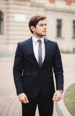 Yakışıklı, şık, genç bir iş adamı. Açık havada portre pozu veriyor.