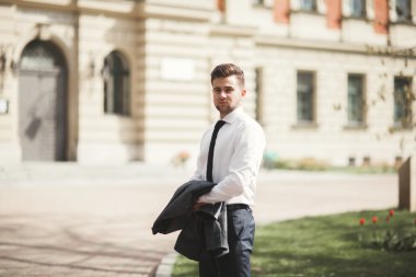 Yakışıklı, şık, genç bir iş adamı. Açık havada portre pozu veriyor.