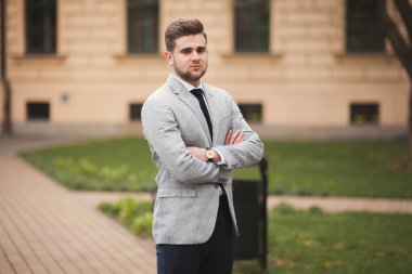 Yakışıklı, şık, genç bir iş adamı. Açık havada portre pozu veriyor.
