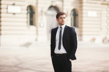 Yakışıklı, şık, genç bir iş adamı. Açık havada portre pozu veriyor.