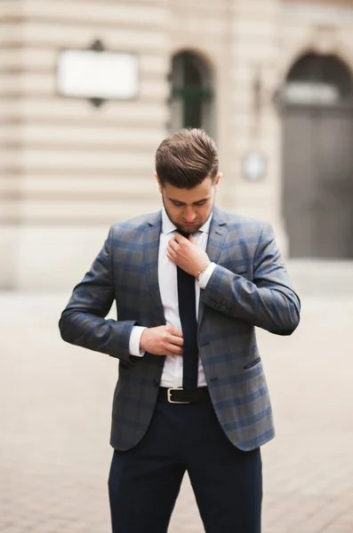 Jovem homem de negócios elegante ajustando seu terno, gravata pescoço — Fotografia de Stock