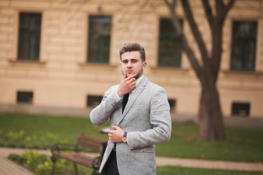 Yakışıklı, şık, genç bir iş adamı. Açık havada portre pozu veriyor.