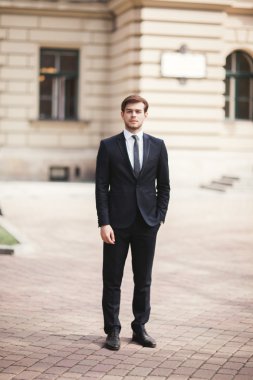 Yakışıklı, şık, genç bir iş adamı. Açık havada portre pozu veriyor.