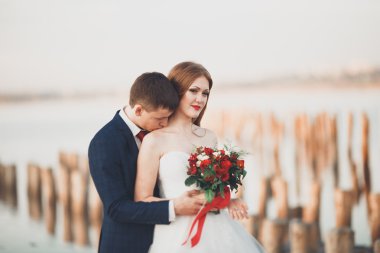 Güzel genç düğün çift, gelin ve damat arka plan denizde ahşap direklerin yakın poz