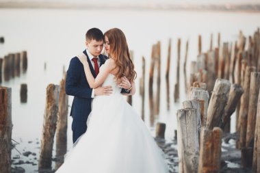 Çift düğün, damat, gelin buketi günbatımı üzerinde denize yakın poz ile