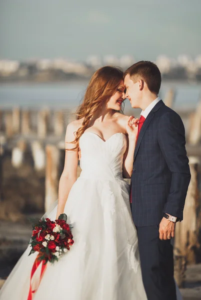 Mariage couple, marié, mariée avec bouquet posant près de la mer au coucher du soleil — Photo