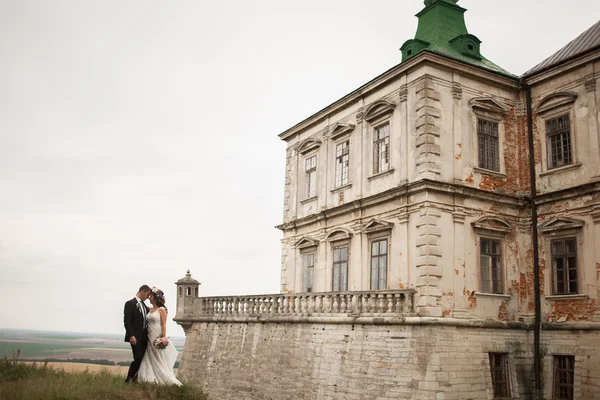 Krásný romantický svatební pár novomanželé objímání v blízkosti starého hradu — Stock fotografie