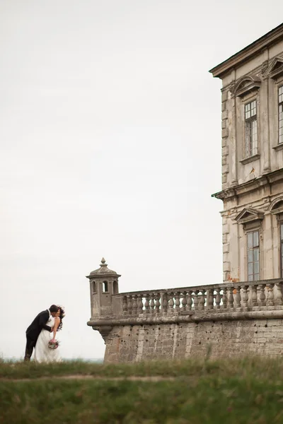 Beautiful romantic wedding couple of newlyweds hugging near old castle — Stock Photo, Image