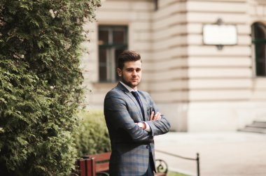 Yakışıklı, şık, genç bir iş adamı. Açık havada portre pozu veriyor.