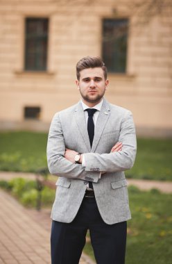Yakışıklı, şık, genç bir iş adamı. Açık havada portre pozu veriyor.