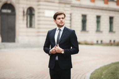 Yakışıklı, şık, genç bir iş adamı. Açık havada portre pozu veriyor.