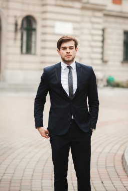 Yakışıklı, şık, genç bir iş adamı. Açık havada portre pozu veriyor.