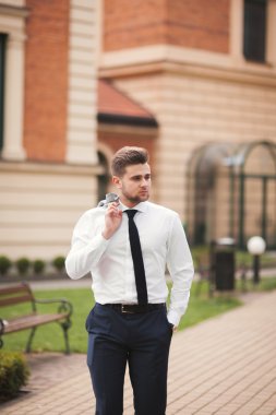 Yakışıklı, şık, genç bir iş adamı. Açık havada portre pozu veriyor.