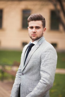 Yakışıklı, şık, genç bir iş adamı. Açık havada portre pozu veriyor.