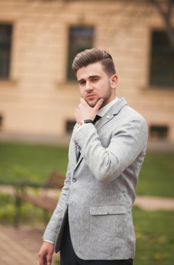 Yakışıklı, şık, genç bir iş adamı. Açık havada portre pozu veriyor.