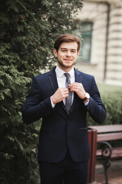 Ung snygg affärsman justera sin kostym, hals slips — Stockfoto