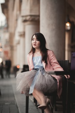 Eski şehir arka plan oturan elbiseli güzel Asyalı kız modeli