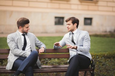 Konuşma ve açık havada gülümseyen iki şık iş adamları