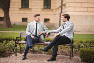 Konuşma ve açık havada gülümseyen iki şık iş adamları