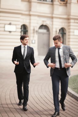 Konuşma ve açık havada gülümseyen iki şık iş adamları