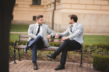 Konuşma ve açık havada gülümseyen iki şık iş adamları