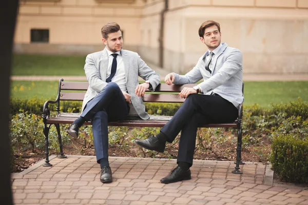 Dos hombres de negocios elegantes hablando y sonriendo al aire libre —  Fotos de Stock