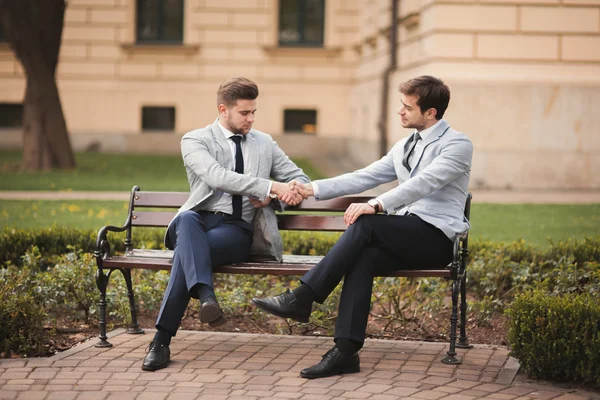 Dois empresários elegantes apertando as mãos em ternos — Fotografia de Stock