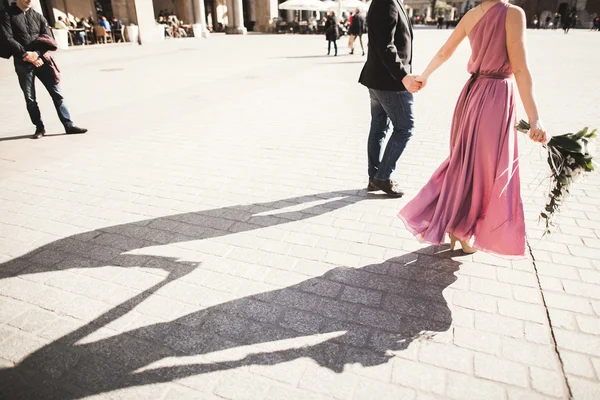 Boda. hermosa pareja, novia con vestido rosa caminando en la vieja ciudad Cracovia, sus sombras — Foto de Stock