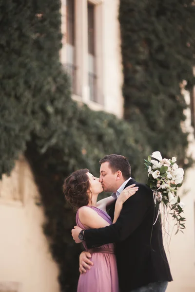 Lyckliga bröllop par, brudgummen, brud med rosa klänning kramas och leende varandra på bakgrunden väggar i slottet — Stockfoto