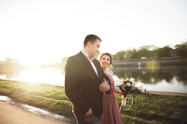 カップルの結婚式、新郎し、日没でガラスと川に近いポーズをドレスアップ — ストック写真