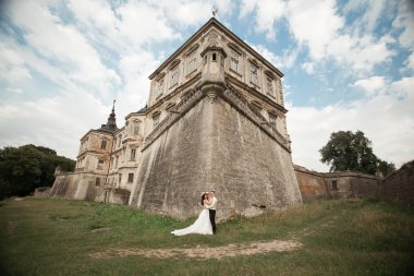 Güzel, romantik bir düğün. Yeni evliler. Eski kalenin yakınlarında sarılıyorlar.