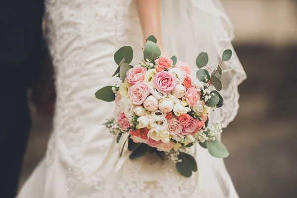 Pretty good wedding bouquet of various flowers in hand