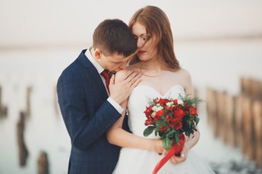 Güzel genç düğün çift, gelin ve damat arka plan denizde ahşap direklerin yakın poz